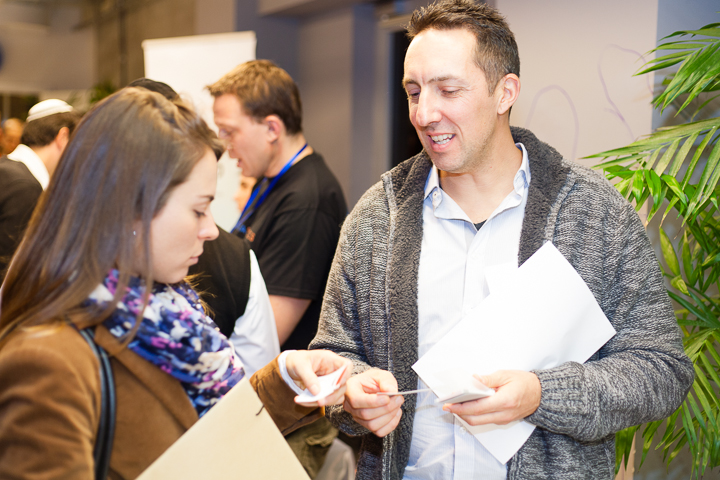 A recent immigrant to Israel exchanges business cards with the QA Manager of Pontis Israel, at a Job Fair focusing on SaaS companies and held at Google TLV Campus.